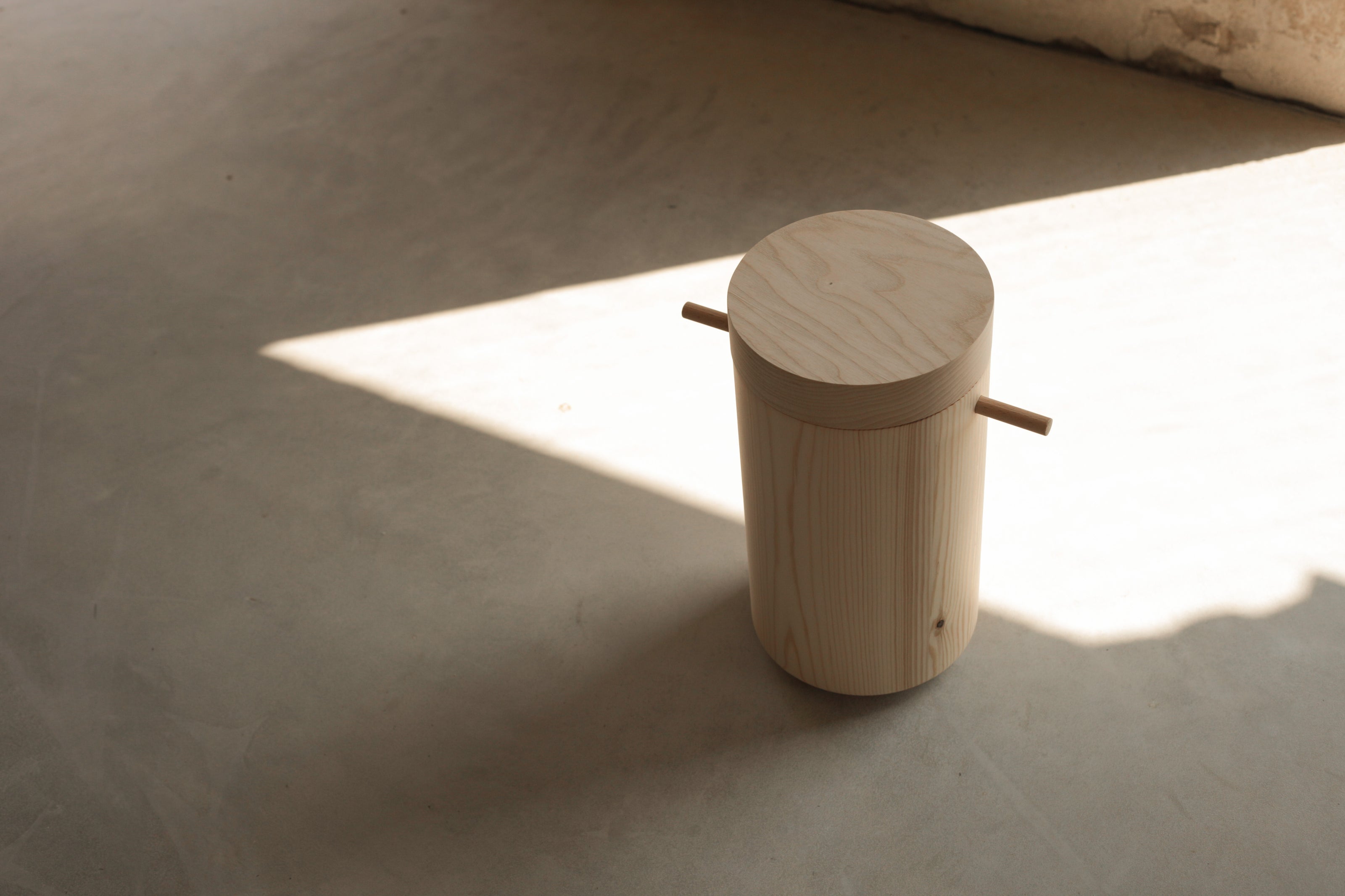 Cylinder shaped, wooden urn on a concreate floor