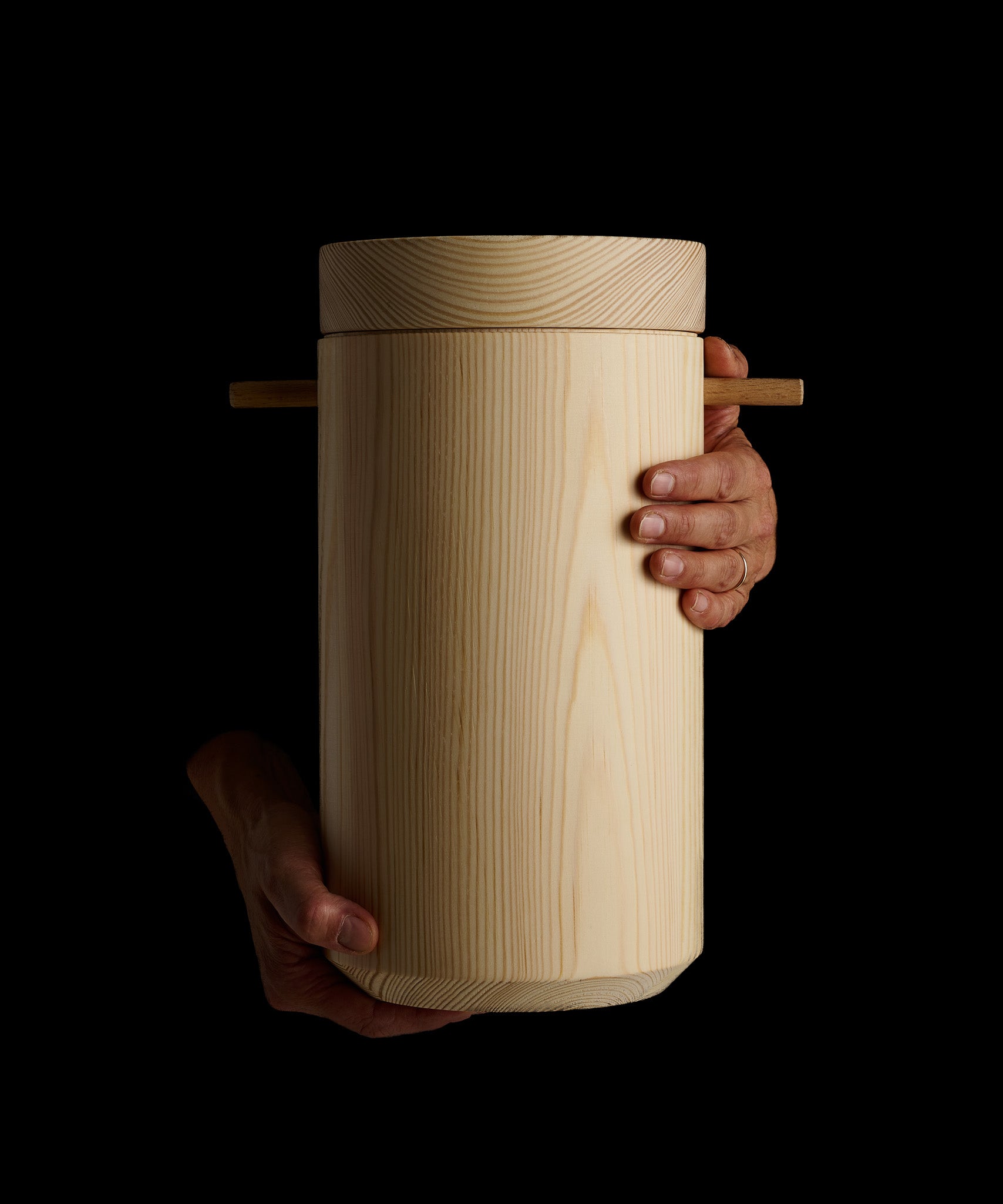 Hands holding a cylinder shaped wooden on a black background