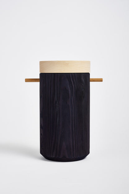 Dark blue colored wooden urn displays on a white table in studio