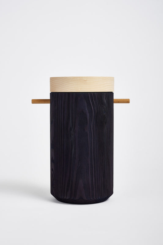 Dark blue colored wooden urn displays on a white table in studio